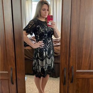 Women’s black lace dress over white/nude slip.